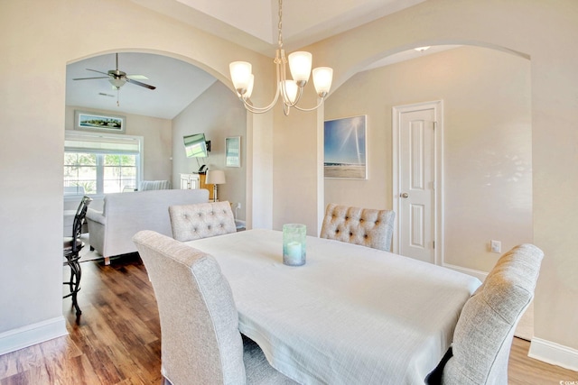 dining space featuring hardwood / wood-style floors, ceiling fan with notable chandelier, and lofted ceiling