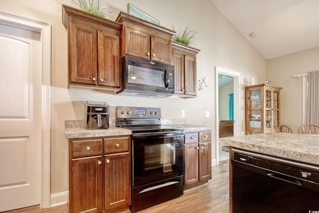 kitchen with black appliances, light wood-type flooring, and lofted ceiling