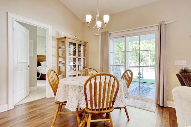 dining area featuring vaulted ceiling, hardwood / wood-style flooring, and an inviting chandelier