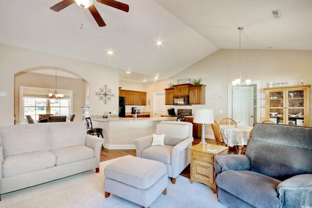 living room featuring light hardwood / wood-style flooring, high vaulted ceiling, and ceiling fan with notable chandelier