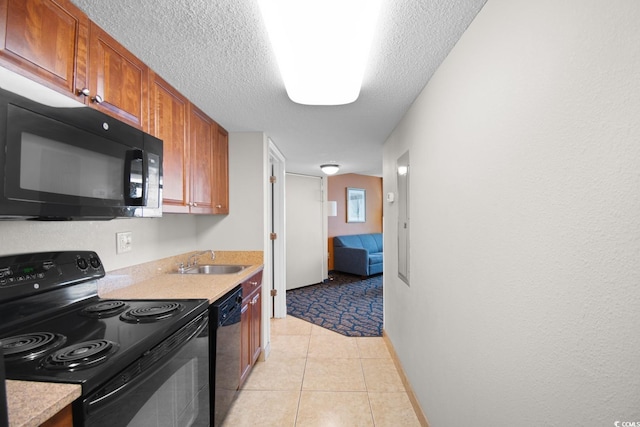 kitchen with sink, light tile patterned floors, black appliances, and a textured ceiling