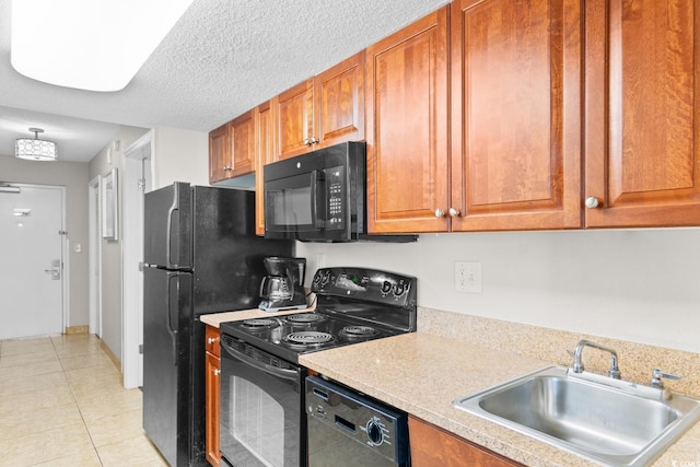 kitchen featuring sink, light tile patterned floors, black appliances, and a textured ceiling