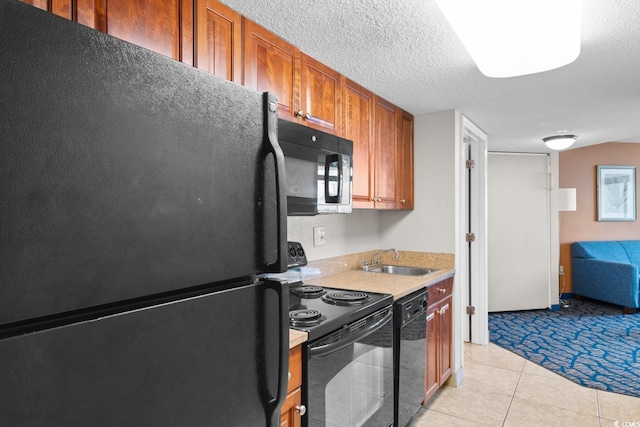 kitchen featuring sink, light tile patterned floors, black appliances, and a textured ceiling