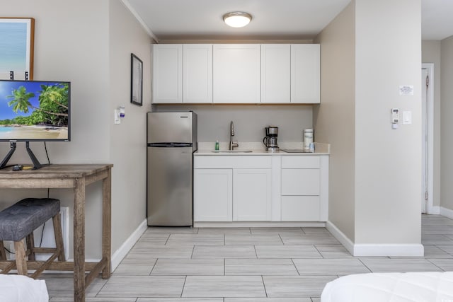 kitchen featuring sink, stainless steel refrigerator, crown molding, and white cabinetry