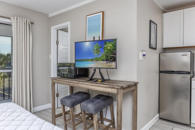 interior space with crown molding and stainless steel refrigerator