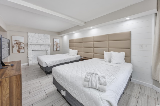 bedroom with beamed ceiling and a stone fireplace