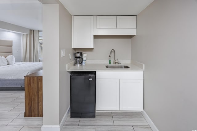 kitchen featuring refrigerator, white cabinets, and sink