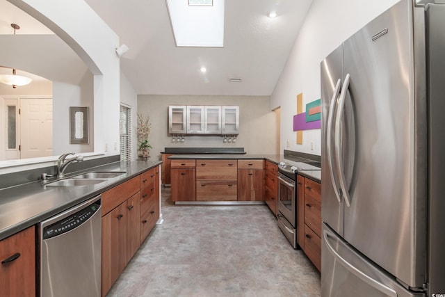 kitchen with sink, kitchen peninsula, lofted ceiling with skylight, pendant lighting, and appliances with stainless steel finishes