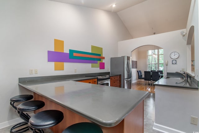 kitchen featuring high vaulted ceiling, a kitchen breakfast bar, sink, kitchen peninsula, and stainless steel appliances