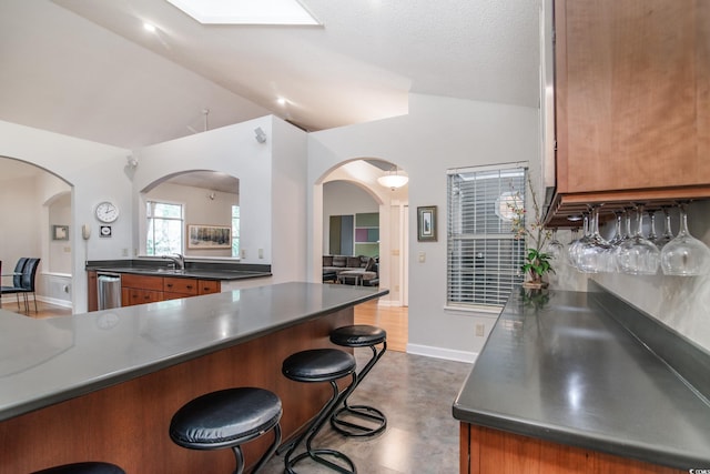 kitchen featuring dishwasher, a kitchen bar, a textured ceiling, and high vaulted ceiling