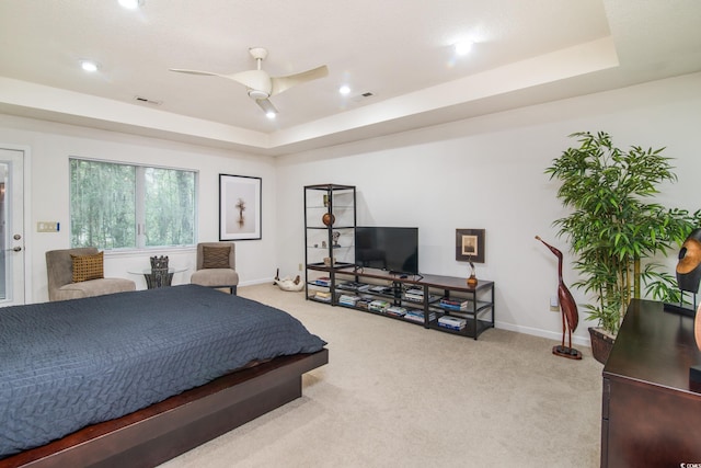 bedroom with a raised ceiling, ceiling fan, and carpet flooring