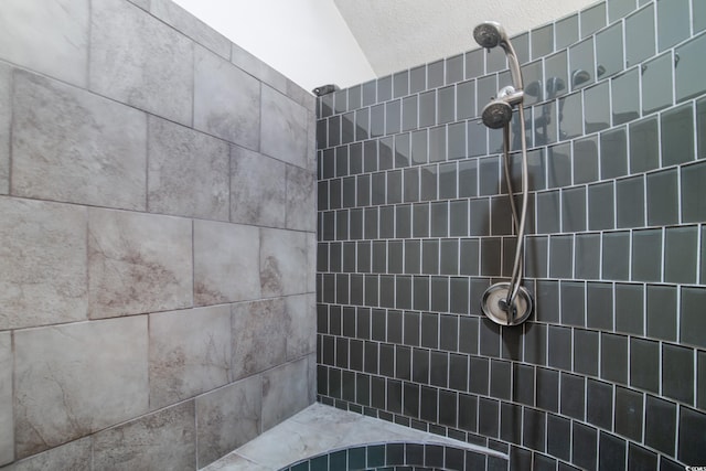 bathroom with a textured ceiling and tiled shower