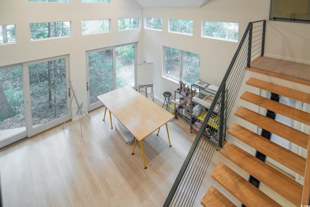 dining room featuring light wood-type flooring and a towering ceiling