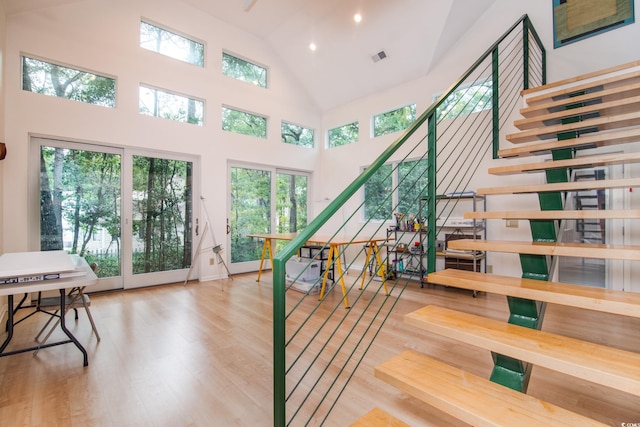 stairs featuring wood-type flooring and high vaulted ceiling