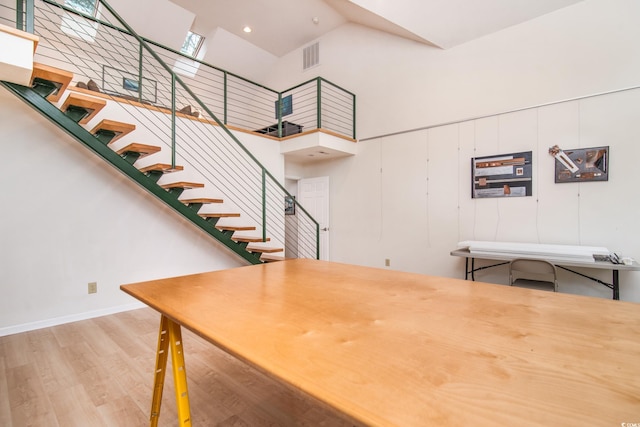 dining space with a towering ceiling and hardwood / wood-style flooring