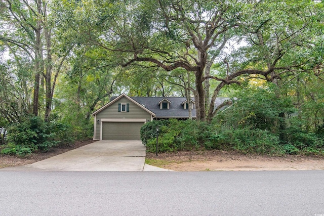 view of property hidden behind natural elements featuring a garage