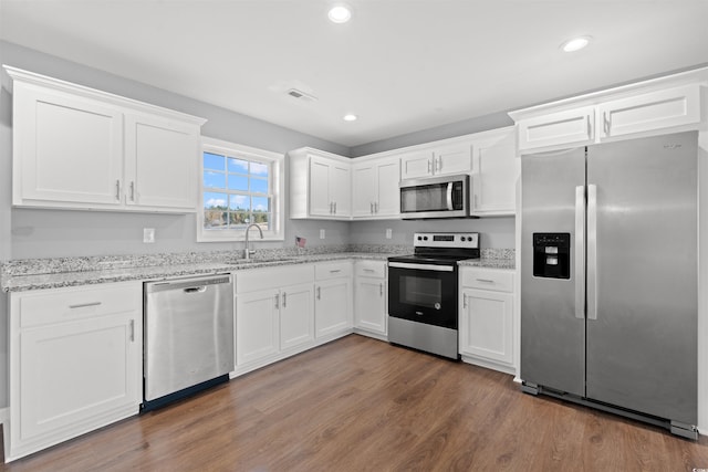 kitchen with white cabinetry, sink, stainless steel appliances, light stone counters, and dark hardwood / wood-style flooring