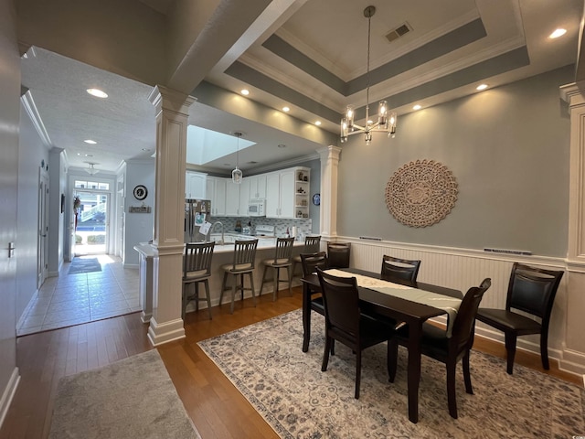 dining room with crown molding, ornate columns, visible vents, and dark wood-style flooring