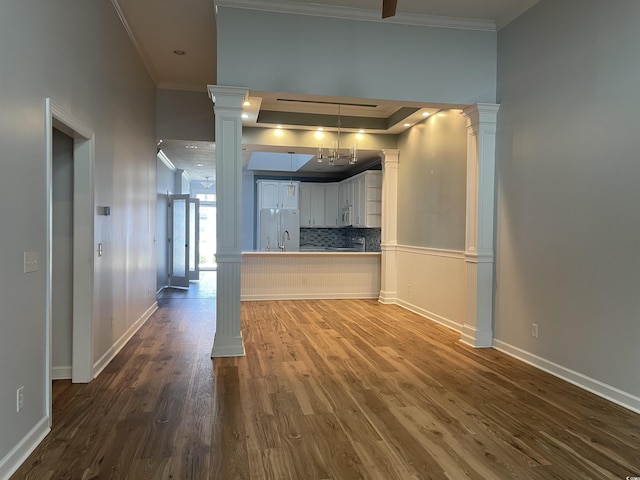 kitchen with ornamental molding, decorative columns, freestanding refrigerator, baseboards, and dark wood finished floors