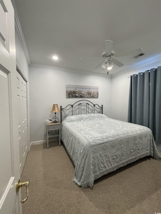 carpeted bedroom featuring ceiling fan, visible vents, baseboards, a closet, and ornamental molding