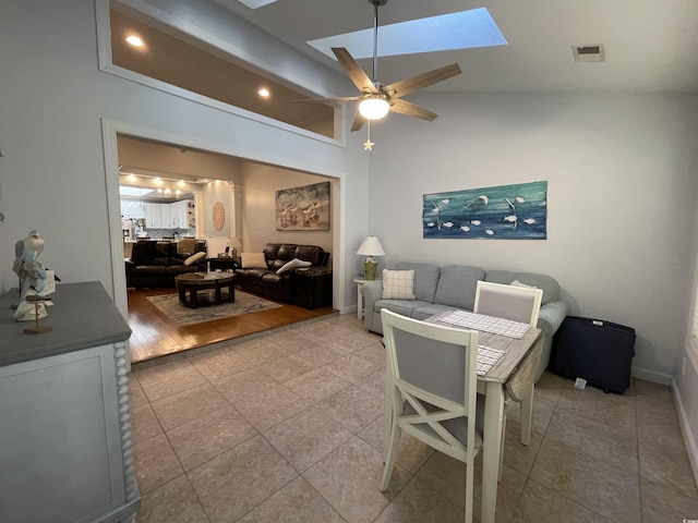 living area featuring visible vents, a ceiling fan, light tile patterned floors, and vaulted ceiling with skylight