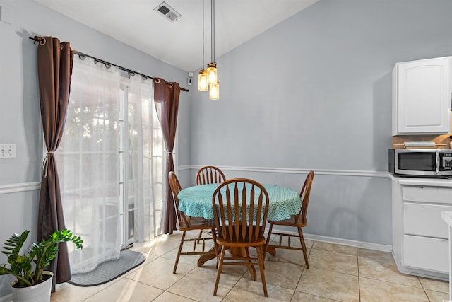 dining space featuring light tile patterned floors and vaulted ceiling