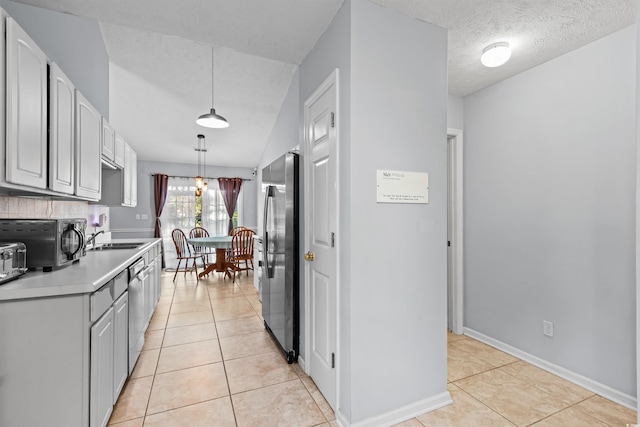 kitchen featuring light tile patterned floors, stainless steel appliances, decorative light fixtures, and sink