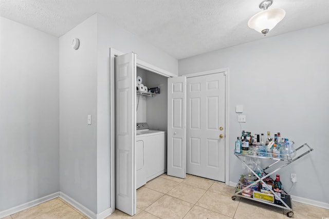 laundry area with washer / clothes dryer, light tile patterned flooring, and a textured ceiling