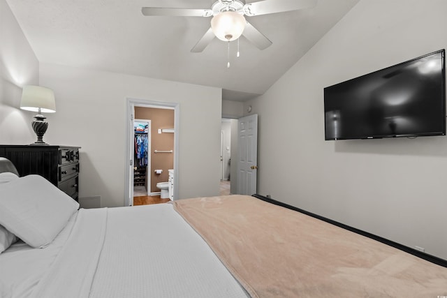 bedroom featuring ceiling fan, a spacious closet, ensuite bathroom, wood-type flooring, and vaulted ceiling