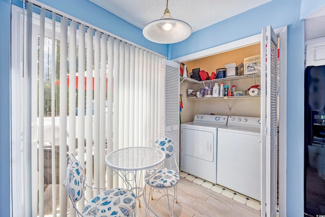 laundry area featuring a textured ceiling, light hardwood / wood-style flooring, and washing machine and clothes dryer