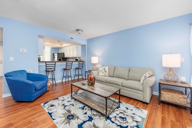 living room featuring a textured ceiling and light hardwood / wood-style flooring