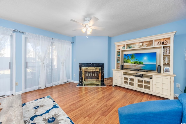 living room with ceiling fan, light hardwood / wood-style floors, and a textured ceiling