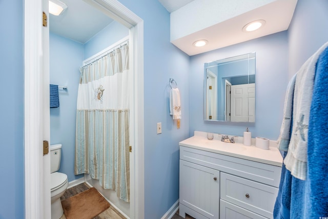 bathroom with hardwood / wood-style floors, vanity, toilet, and walk in shower