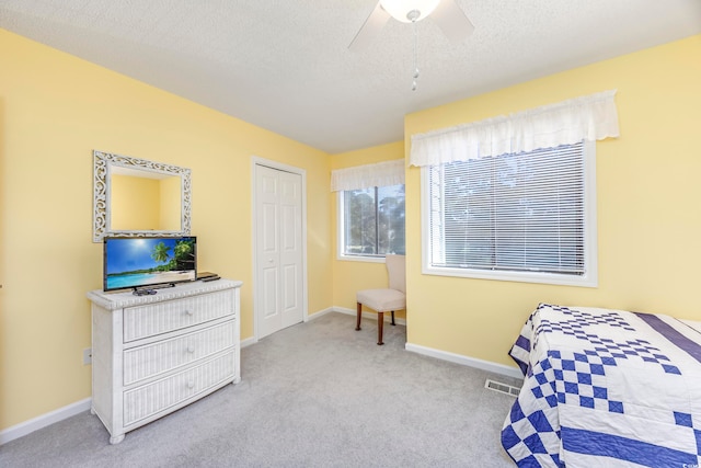 bedroom featuring a closet, a textured ceiling, light colored carpet, and ceiling fan