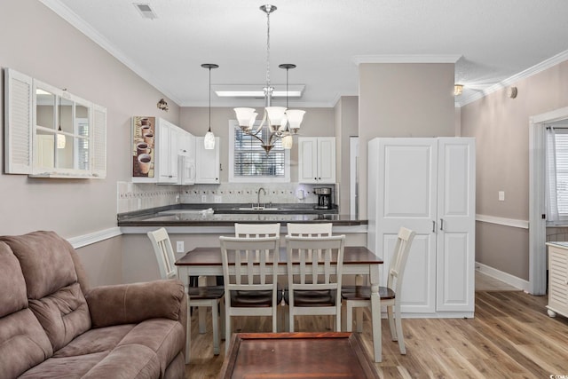 kitchen featuring a wealth of natural light, white cabinetry, hanging light fixtures, and ornamental molding