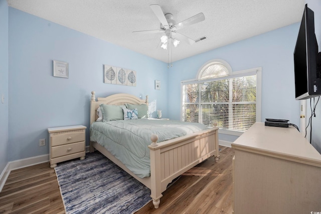 bedroom featuring a textured ceiling, dark hardwood / wood-style floors, and ceiling fan