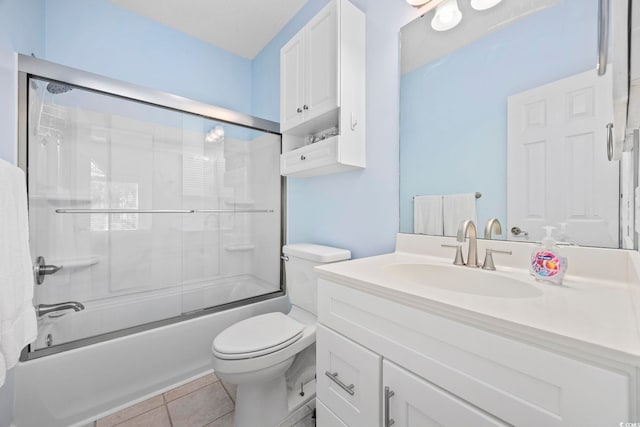 full bathroom featuring tile patterned flooring, vanity, toilet, and bath / shower combo with glass door