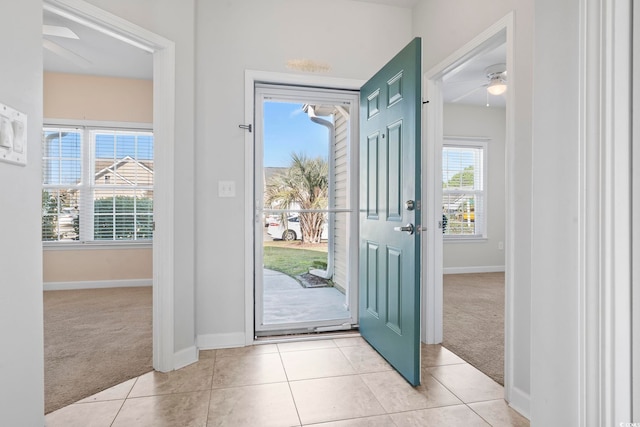 doorway with ceiling fan and light colored carpet