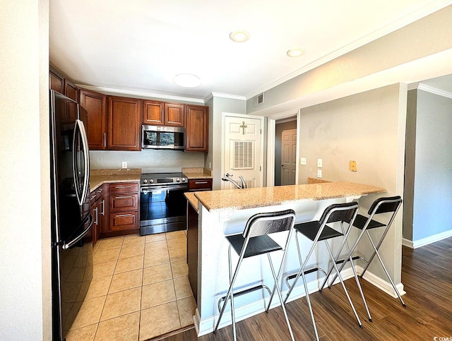 kitchen with a kitchen breakfast bar, crown molding, light hardwood / wood-style flooring, kitchen peninsula, and stainless steel appliances