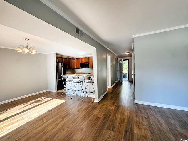 kitchen with black appliances, dark hardwood / wood-style floors, a kitchen bar, and crown molding