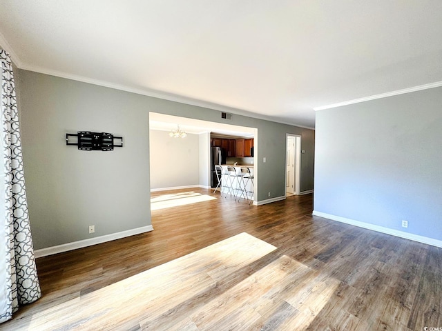 unfurnished living room featuring a notable chandelier, wood-type flooring, and crown molding