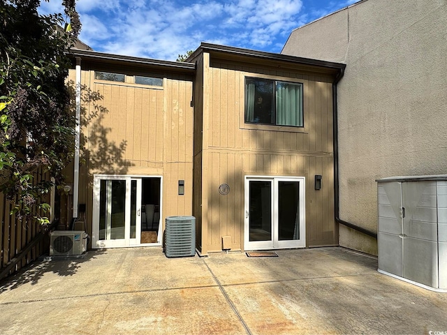 back of property with ac unit, central AC, and a patio area