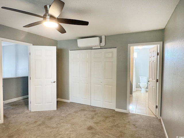 unfurnished bedroom with light colored carpet, a wall unit AC, ceiling fan, connected bathroom, and a closet