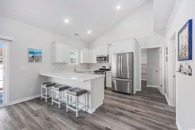 kitchen with white cabinetry, sink, a breakfast bar area, kitchen peninsula, and stainless steel appliances