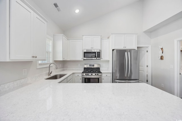 kitchen featuring lofted ceiling, appliances with stainless steel finishes, sink, and white cabinets