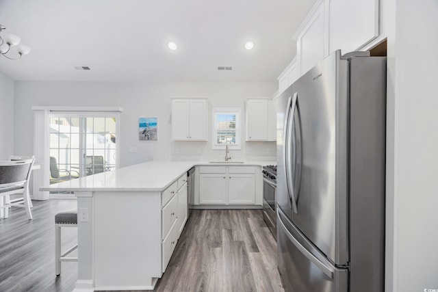 kitchen with sink, a breakfast bar area, appliances with stainless steel finishes, white cabinetry, and kitchen peninsula