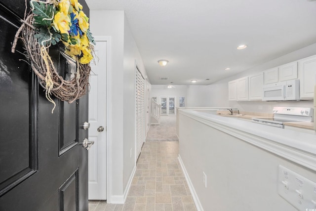 interior space featuring white cabinets, white appliances, and sink