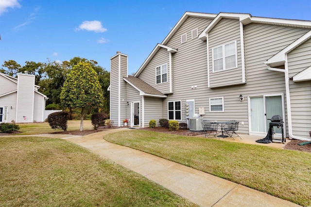 rear view of house featuring cooling unit, a patio area, and a yard