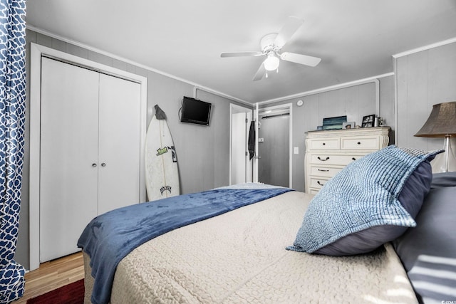 bedroom featuring wood-type flooring, a closet, ceiling fan, and crown molding