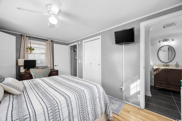 bedroom with ceiling fan, sink, wood-type flooring, connected bathroom, and a closet